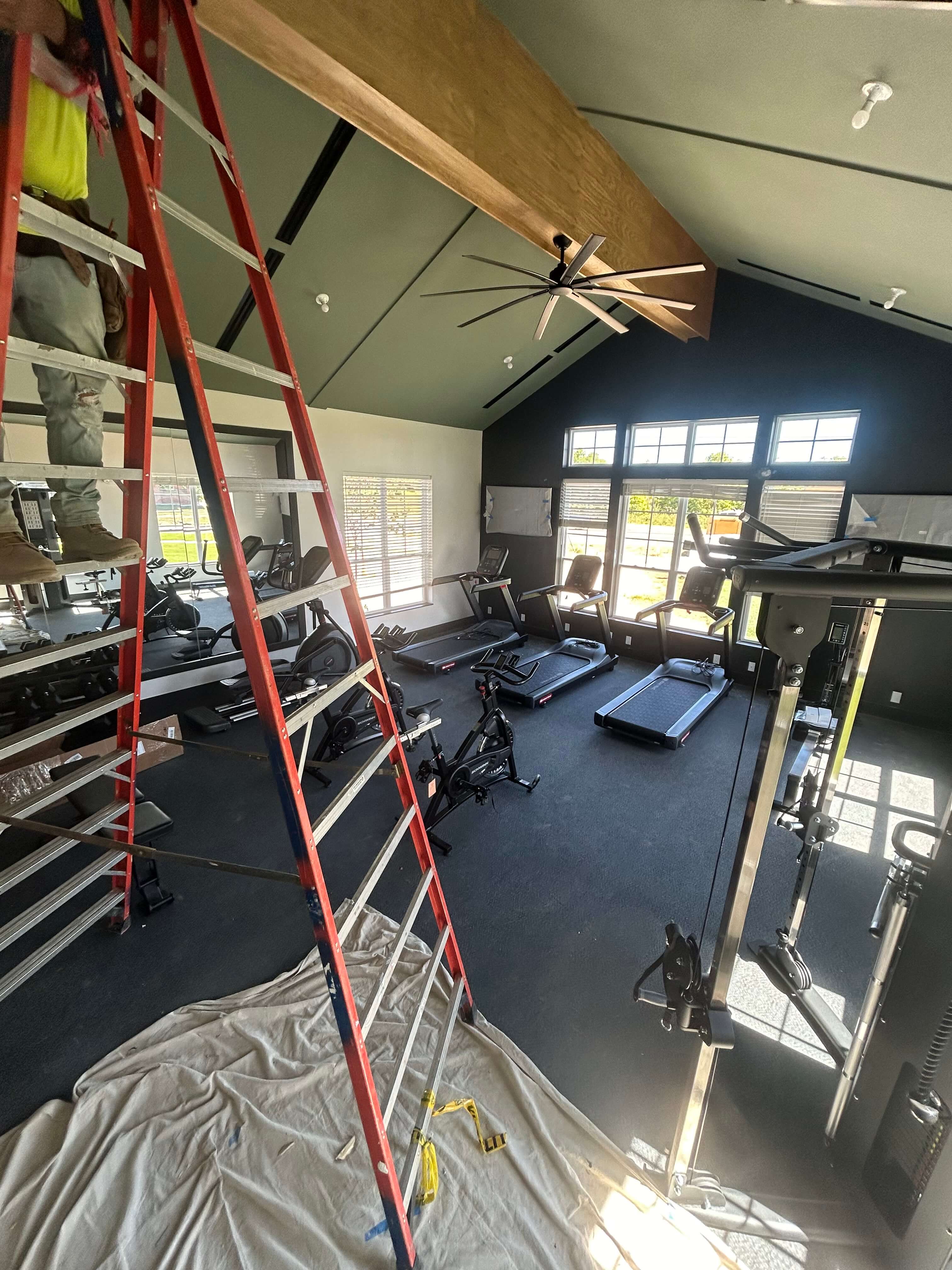 Progress photo of fitness center with treadmills and ceiling fan during electrical rough-in